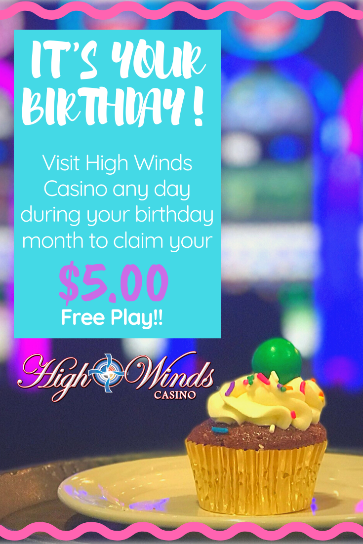 The image promotes a birthday special at High Winds Casino, featuring a cupcake with colorful sprinkles and a green gumball on top. The text reads: 'It’s your birthday! Visit High Winds Casino any day during your birthday month to claim your $5.00 Free Play!' The background is blurred with vibrant casino lights, and the High Winds Casino logo is featured at the bottom.